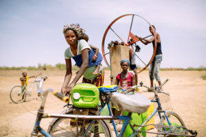 Barry Aliman, 24 years old, bicycles with her baby to fetch water for her family, Sorobouly village near Boromo, Burkina Faso. Climate change will affect rainfall patterns and the availability of water. Photo: Ollivier Girard/CIFOR